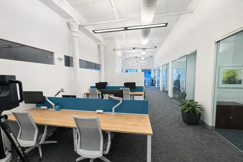 Modern open office workspace with shared desks, private offices, and glass meeting rooms