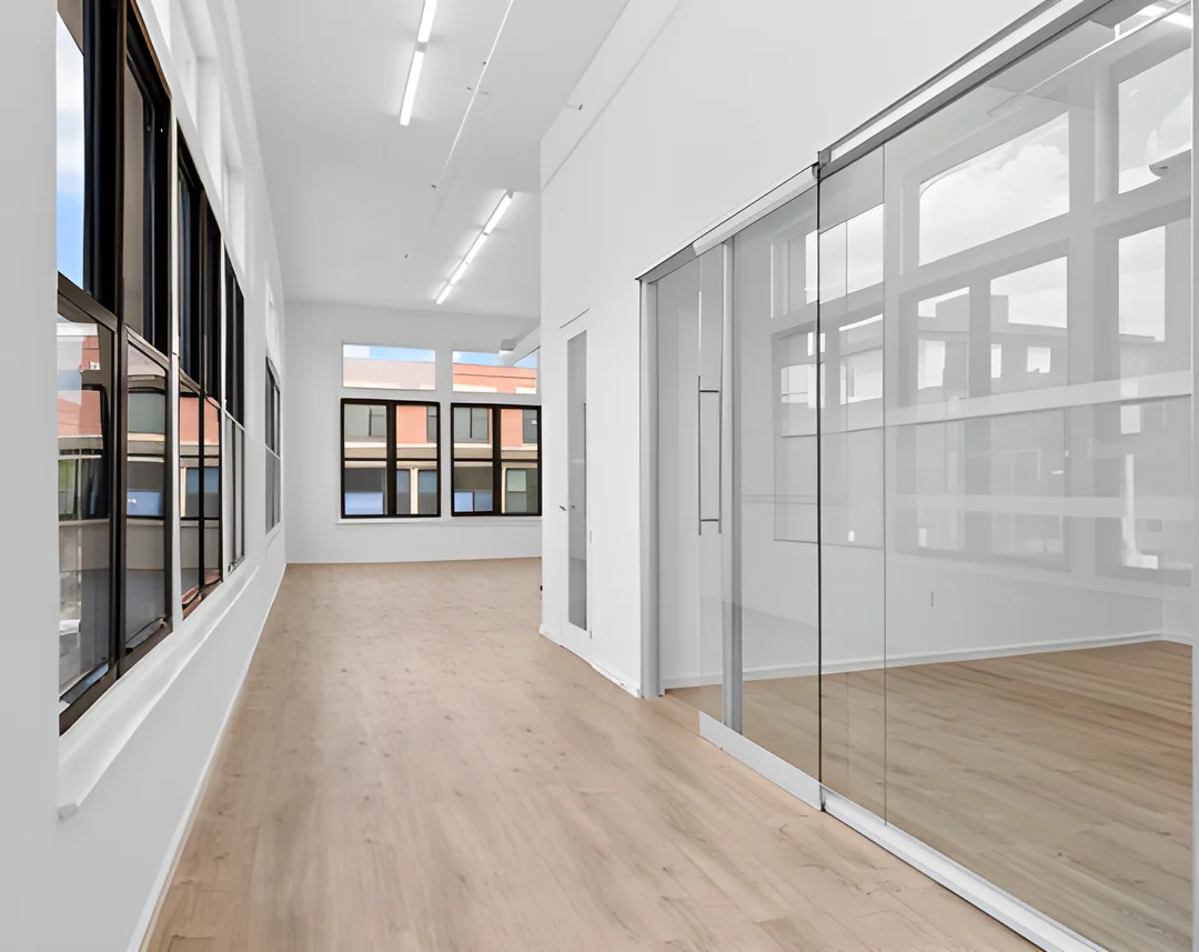 Modern private office space with glass conference room, natural light, and hardwood floors in a flexible workspace