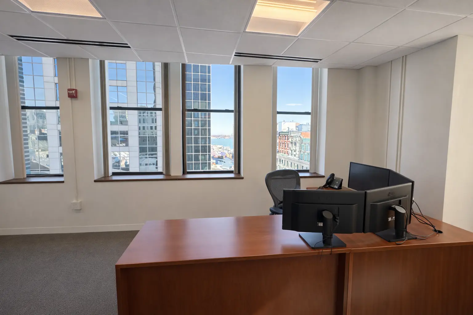 Private office with desk setup and large windows overlooking downtown buildings