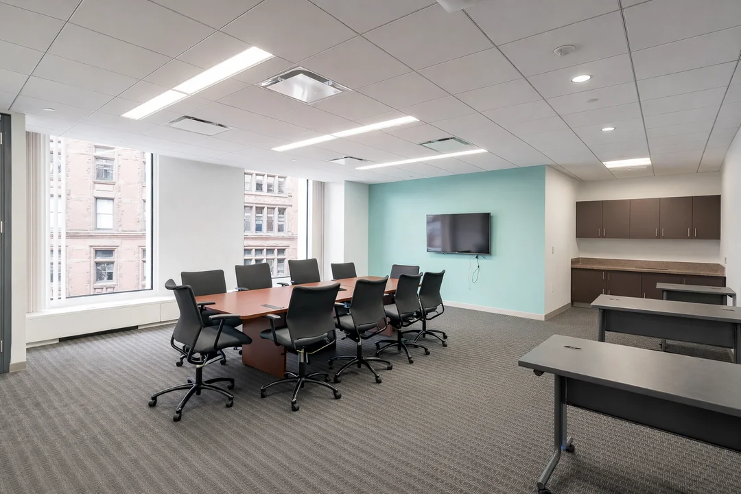 Modern conference room with large windows, long meeting table, and wall-mounted TV.