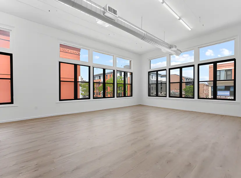 Bright open office space with large windows, natural light, and hardwood floors