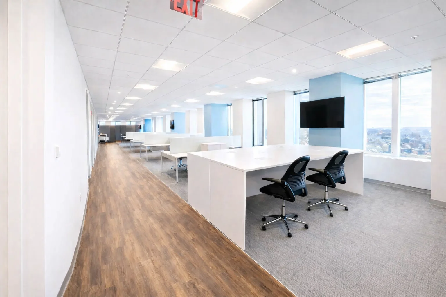 Bright open-plan office with shared desks, large windows, and city views